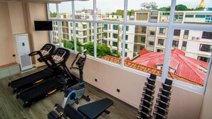 Un gimnasio con cintas de correr, una bicicleta estática y un banco.