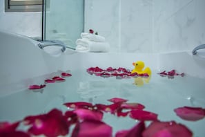 A bathtub with rose petals and a rubber duck. - Rose Villa Residence (Yangon)