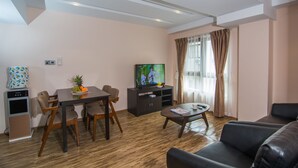 Una sala de estar moderna con una mesa de comedor, sillas, un sofá, una televisión y una mesa de centro.