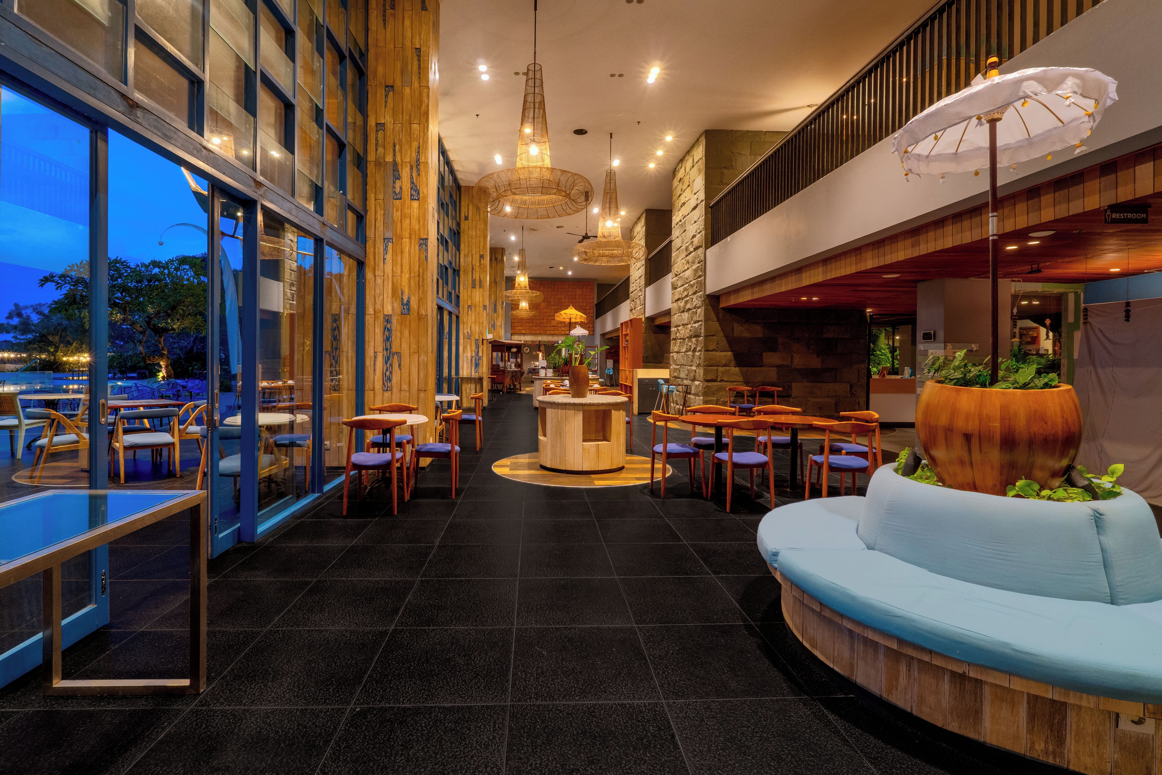 Un interior moderno con una zona de bar central, espacios de asiento y vistas amplias a través de grandes ventanales.