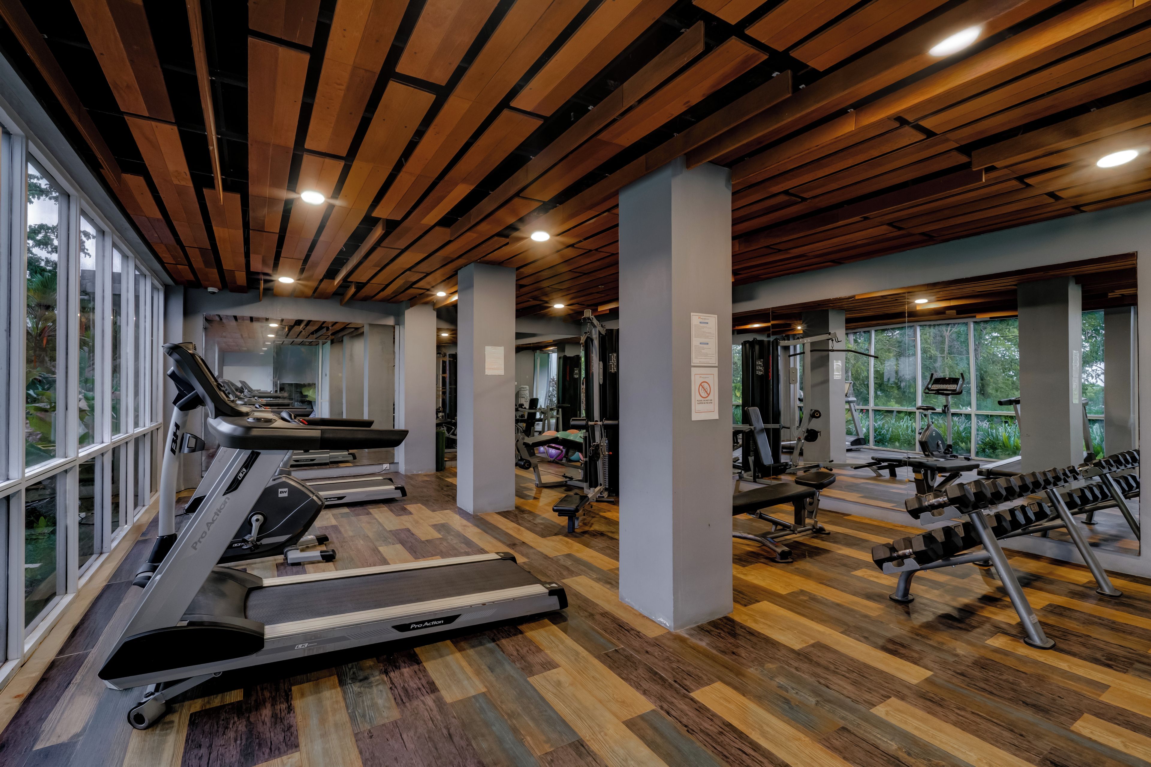 Un gimnasio con cintas de correr, máquinas de pesas y colchonetas de ejercicio.