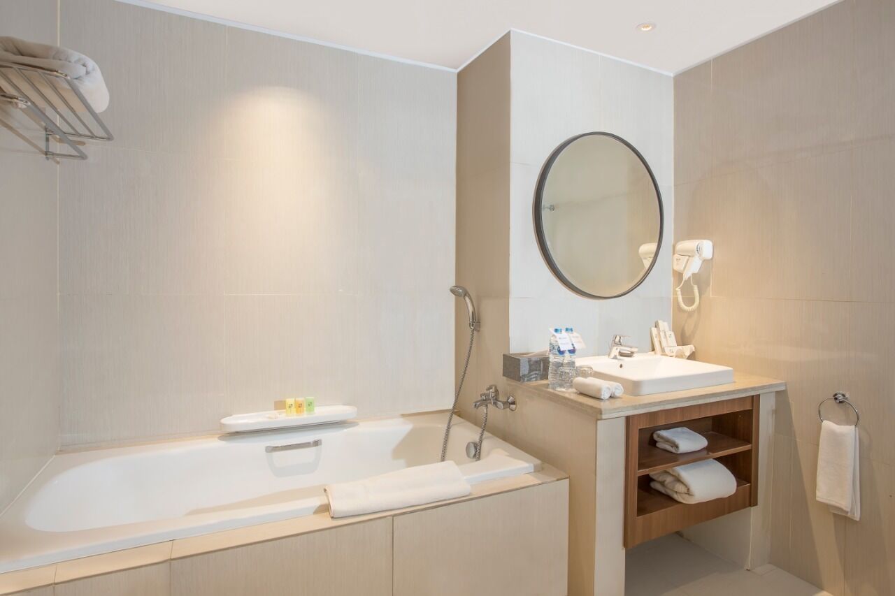 A modern bathroom with a bathtub, a sink, a mirror, and a towel rack.