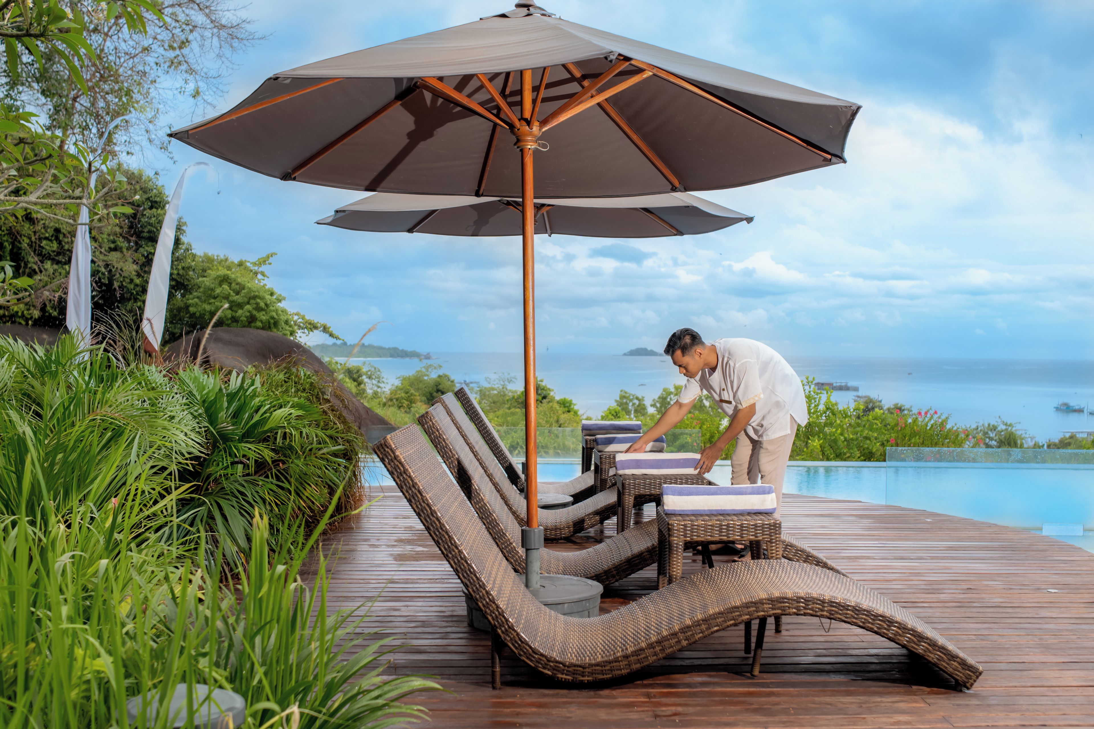 A wooden deck with lounge chairs and an umbrella, overlooking a body of water.