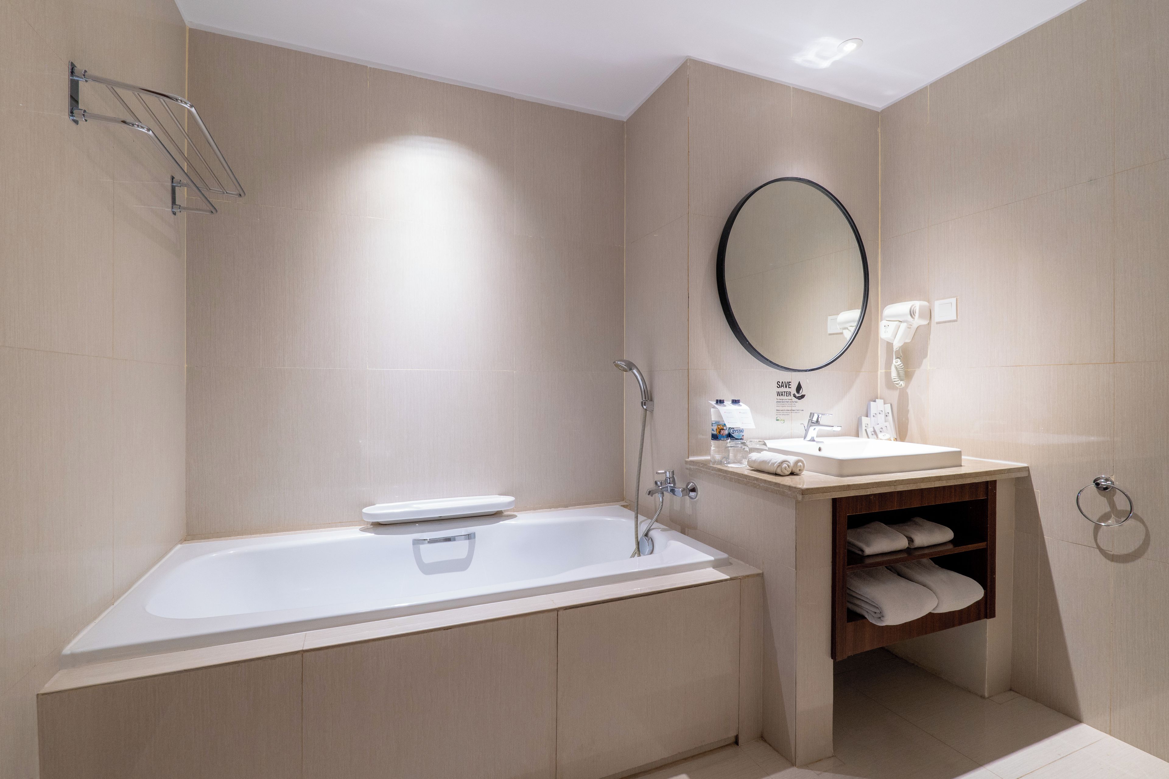 A modern bathroom with a freestanding bathtub, a round mirror, a sink, and a towel rack.