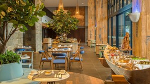 A restaurant with a central dining area, a buffet, and a large potted plant.