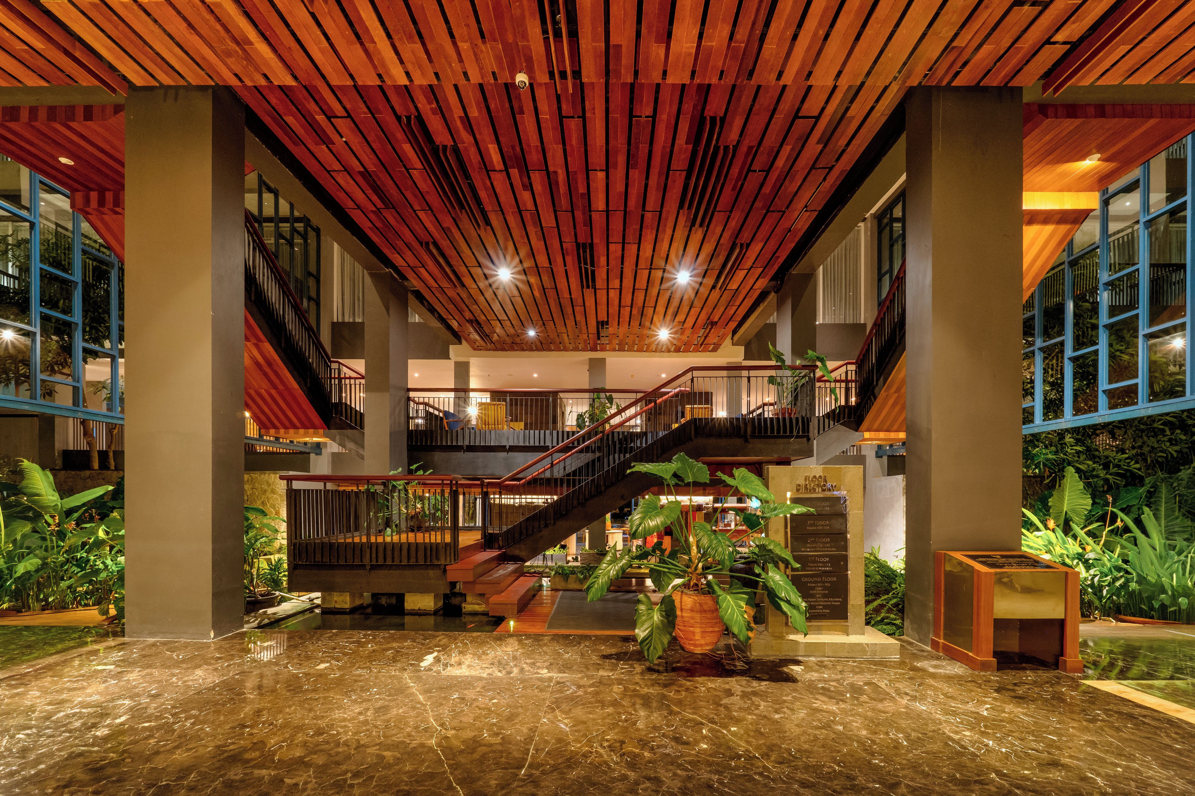 A spacious lobby with a wooden ceiling, a central staircase, and a water feature.