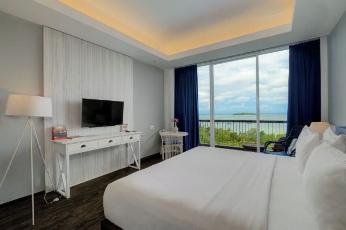 Une chambre d’hôtel avec un grand lit, un bureau doté d’un téléviseur à écran plat, une petite table et un balcon avec vue.