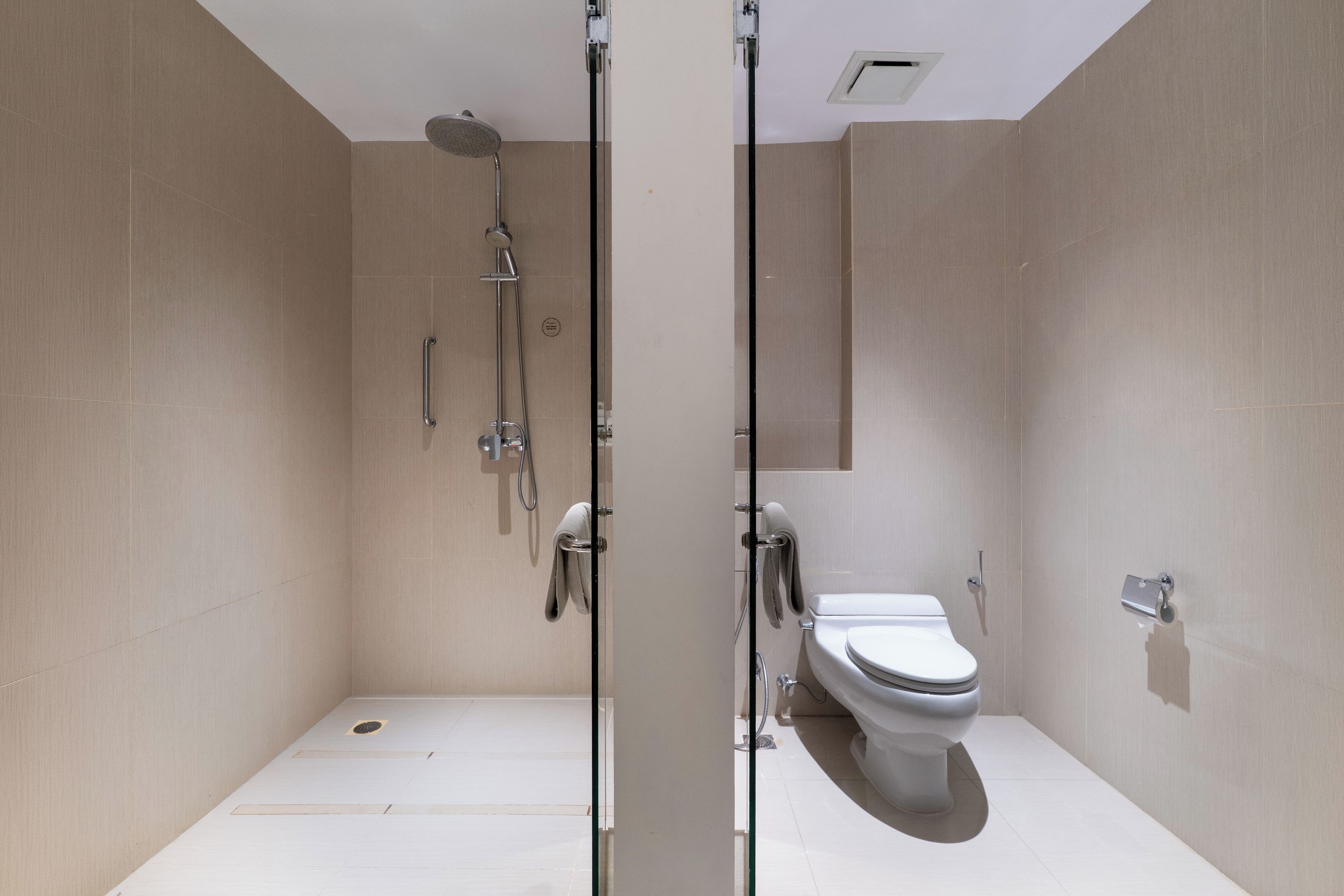 A modern bathroom with a shower, toilet, and a glass partition.