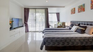 A modern bedroom with two beds, a TV, and artwork on the walls. - The Kris BangTao by Lofty (Choeng Thale)