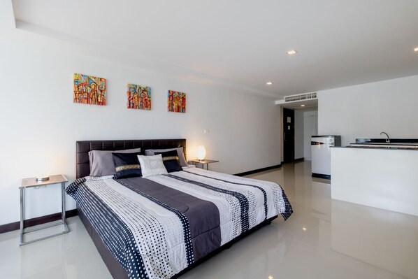 A modern hotel room with a large bed, a desk, and a kitchenette. - The Kris BangTao by Lofty (Choeng Thale)