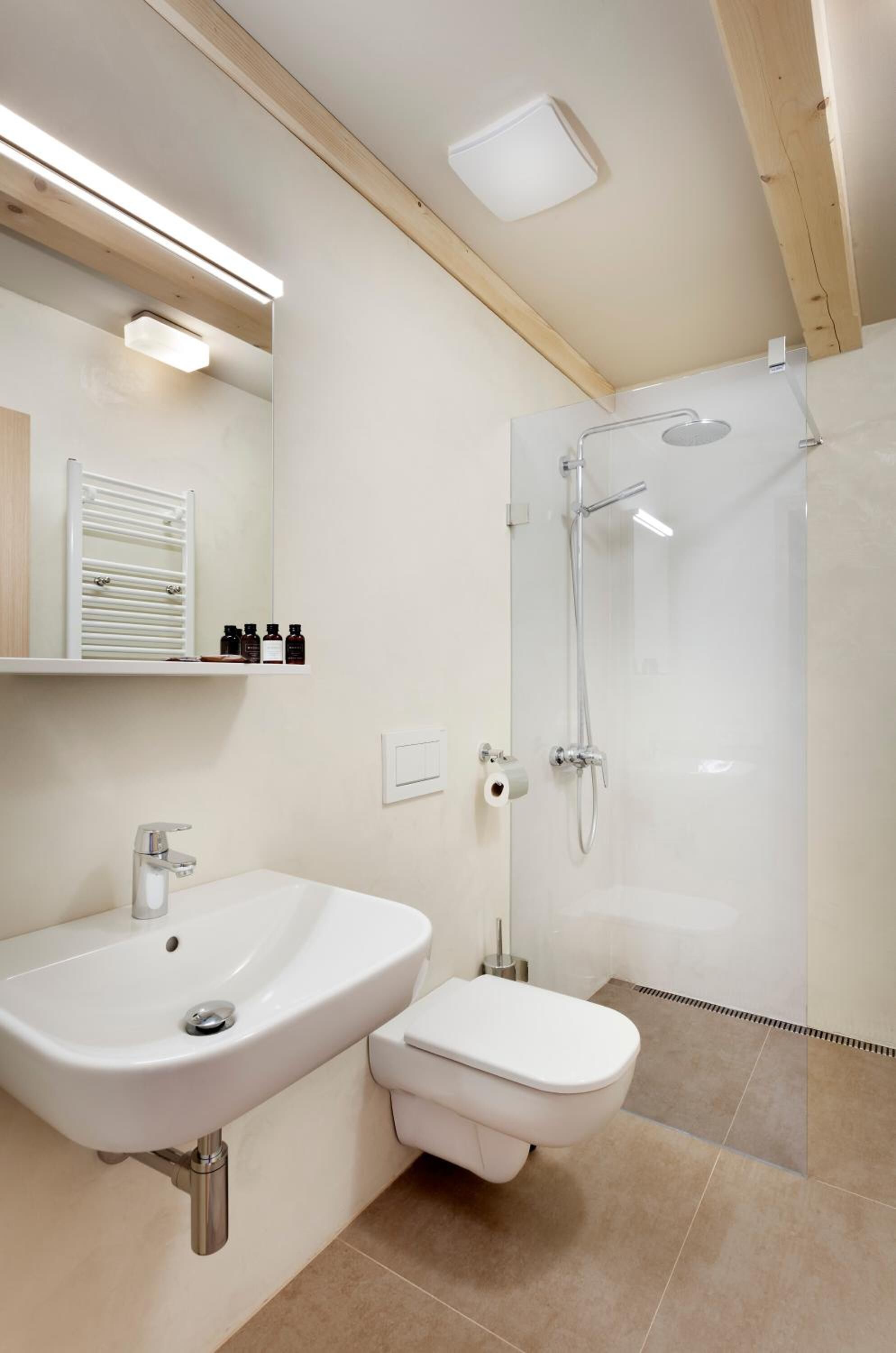 A modern bathroom with a white sink, toilet, and glass-enclosed shower.