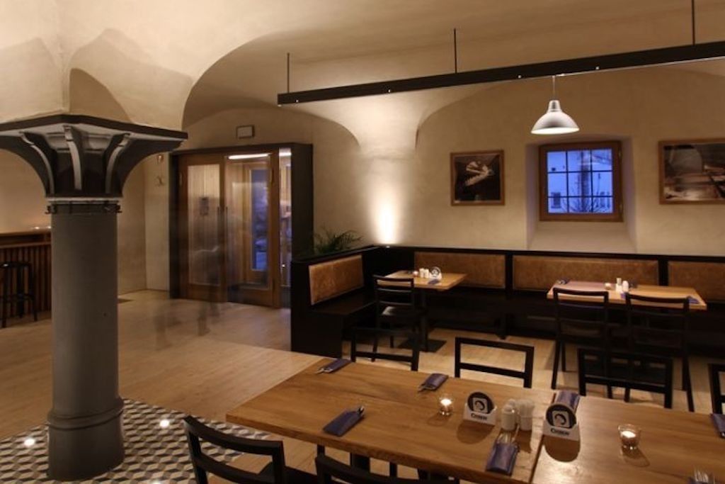 Un restaurant avec des tables et des bancs en bois, une colonne et des tableaux encadrés accrochés aux murs.