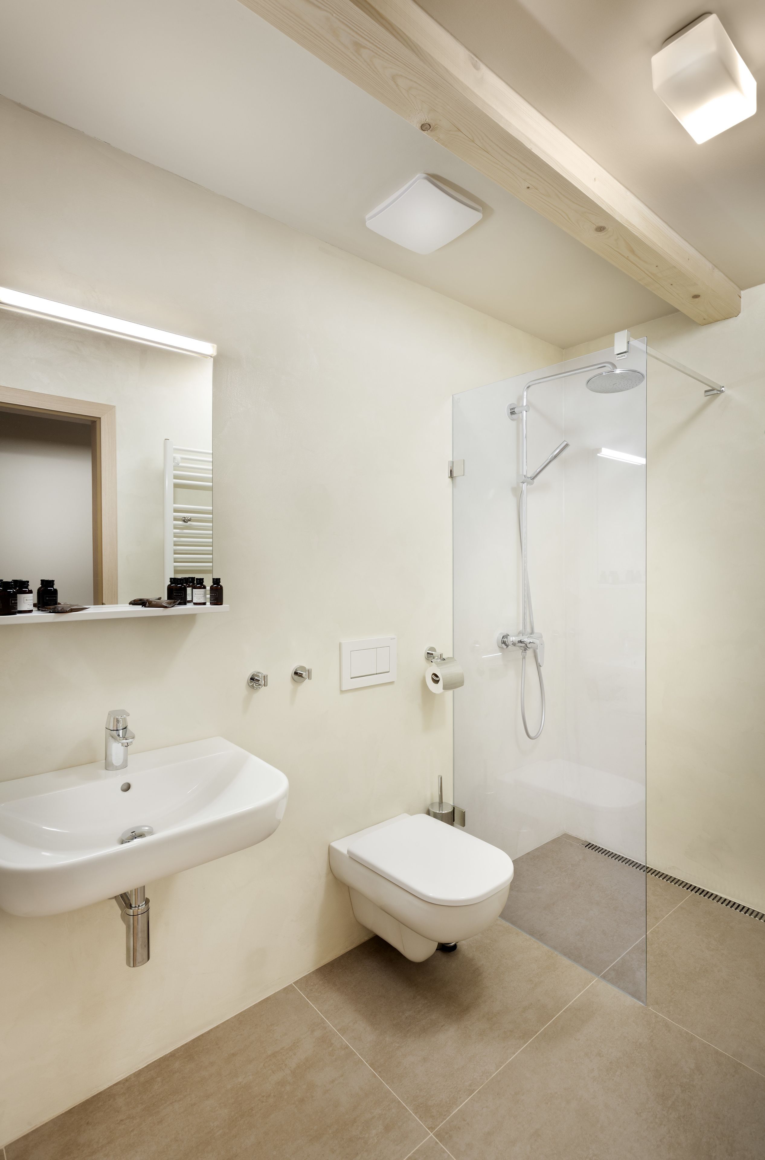 Un baño moderno con lavamanos, inodoro y ducha con mampara de vidrio.