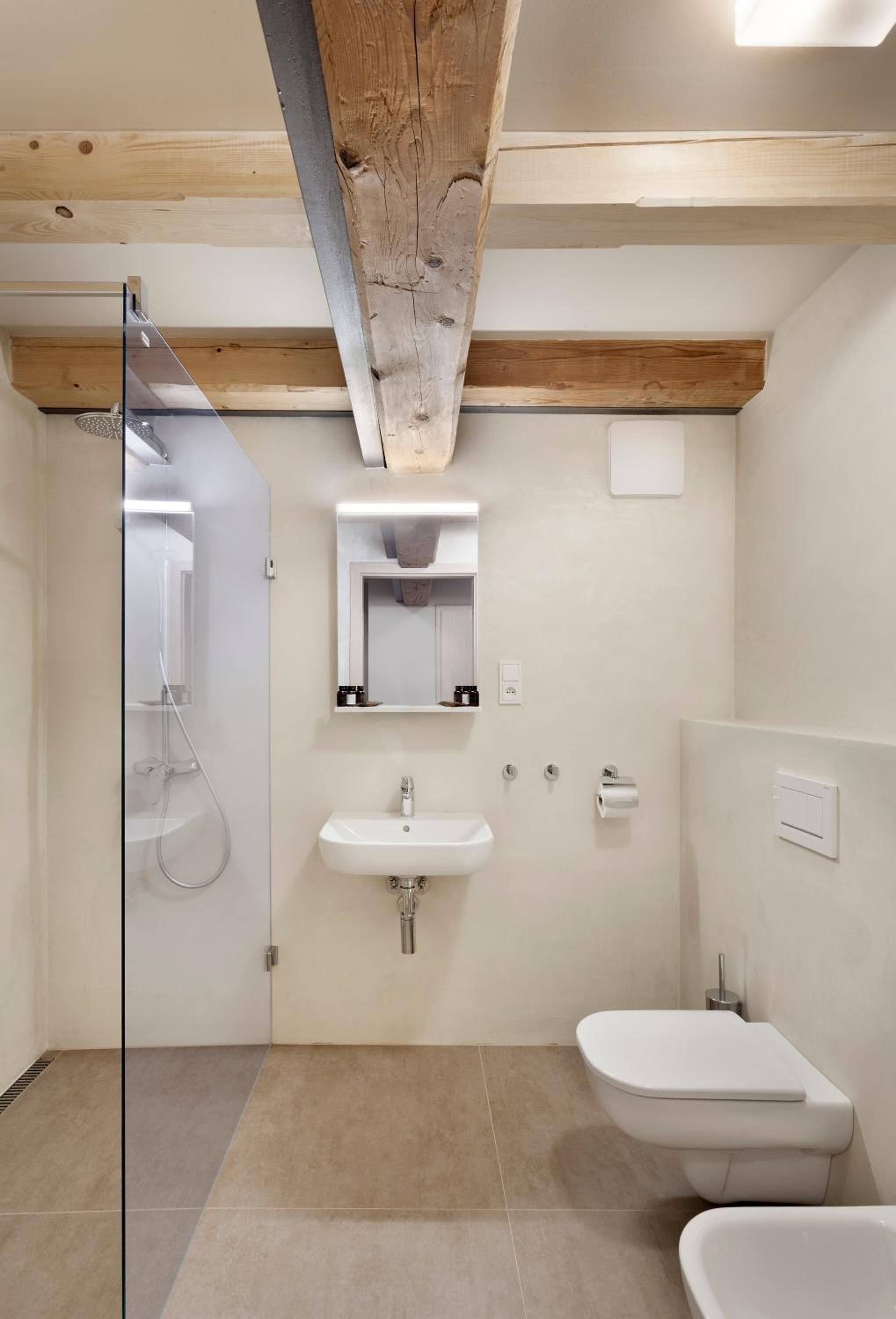 Un baño moderno con cabina de ducha de vidrio, un lavamanos y un inodoro.