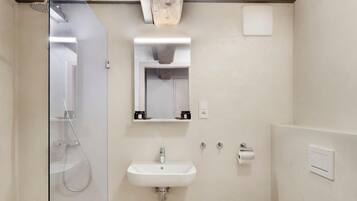 Un baño moderno con cabina de ducha de vidrio, un lavamanos y un inodoro.