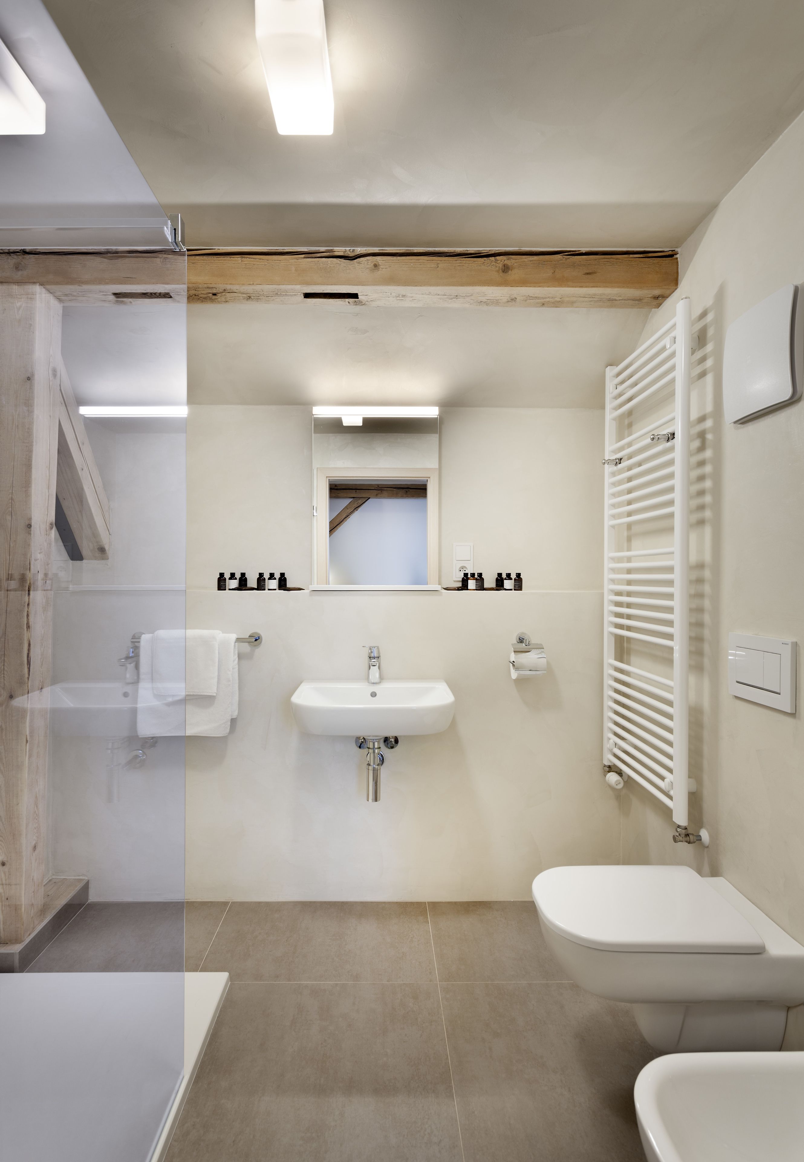 A modern bathroom with a glass shower, a sink, and a toilet.