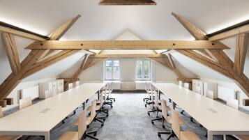 Une salle de conférence avec un plafond haut, des poutres en bois et de grandes fenêtres.