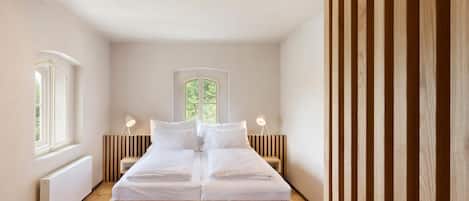 A bedroom with a wooden bed, two bedside tables, a window, and a radiator.