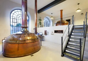 A spacious interior with a large copper still, a staircase, and arched windows. - Hotel Kleis (Cvikov)