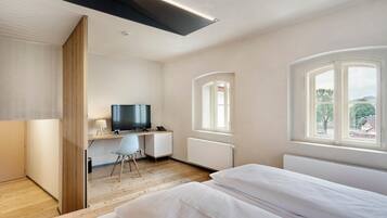 Ein modernes Schlafzimmer mit Bett, Schreibtisch, Stuhl und Fernseher.