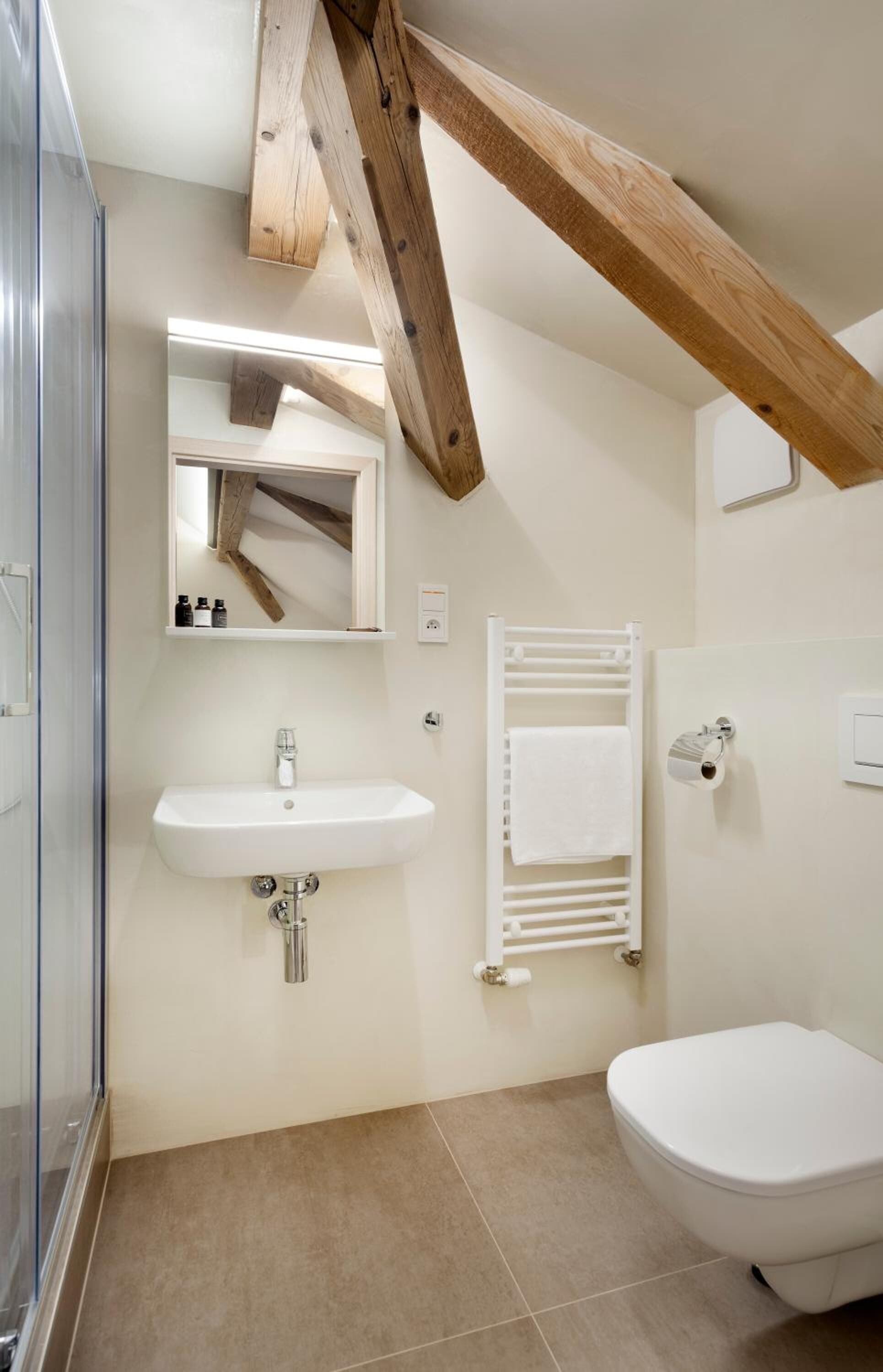 A bathroom with a white sink, a toilet, a towel rack, and a mirror.