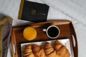 A breakfast tray with croissants, orange juice, and coffee on a wooden tray, accompanied by a black booklet with gold text. - Forbes Retreat - Donnini Apartments (Ayr)
