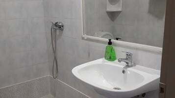 Un baño con ducha, lavabo y espejo.