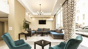 A modern living room with teal chairs, a sofa, a coffee table, and a flat-screen TV mounted on the wall.