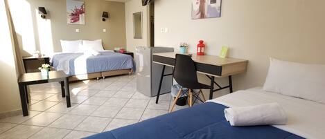 Una habitación de hotel con cama, escritorio, silla y una pequeña kitchenette.