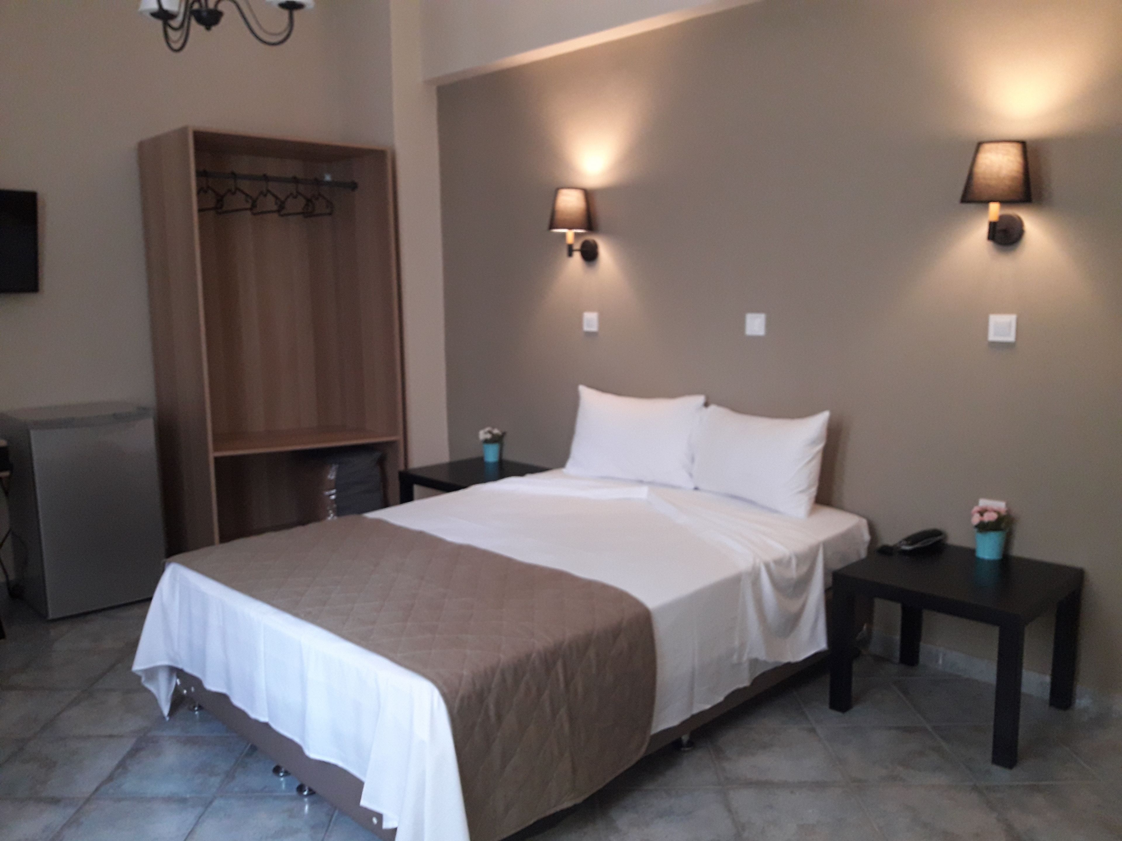 Una habitación de hotel con cama, mesitas de noche, armario y escritorio.