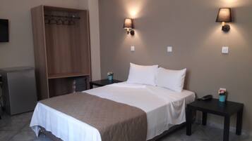 A hotel room with a bed, bedside tables, a wardrobe, and a desk.