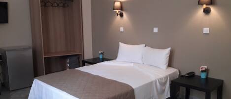 Una habitación de hotel con cama, mesitas de noche, armario y escritorio.
