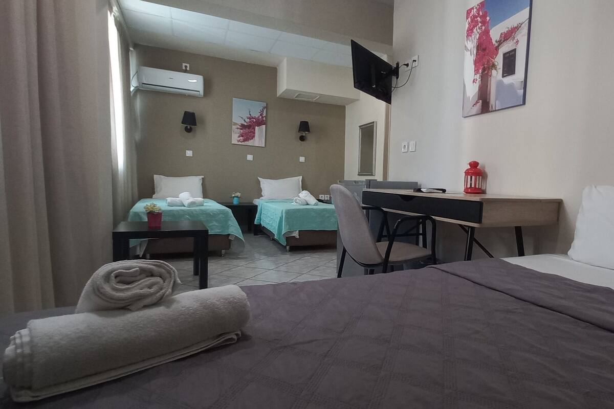Hotellihuone, jossa on kaksi sänkyä, työpöytä, tuoli, televisio ja taulu seinällä.