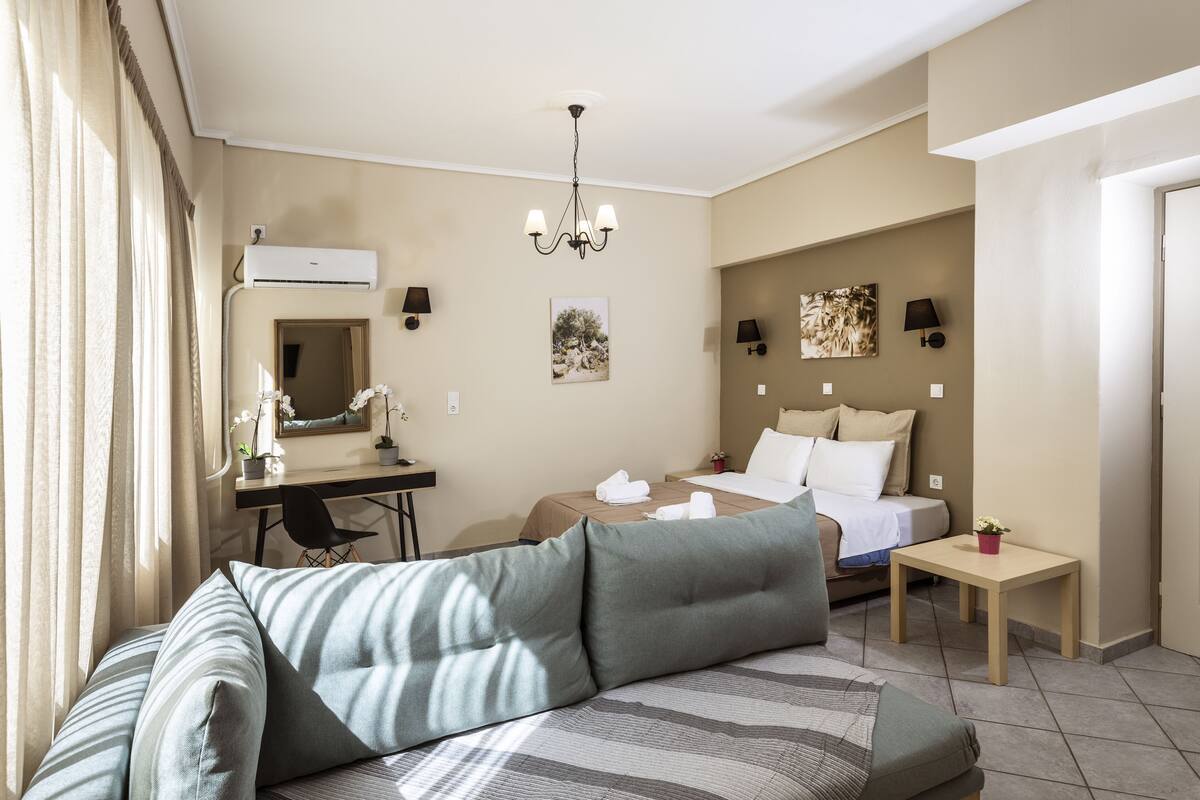 Hotellihuone, jossa on sohva, sänky, työpöytä ja pieni pöytä.