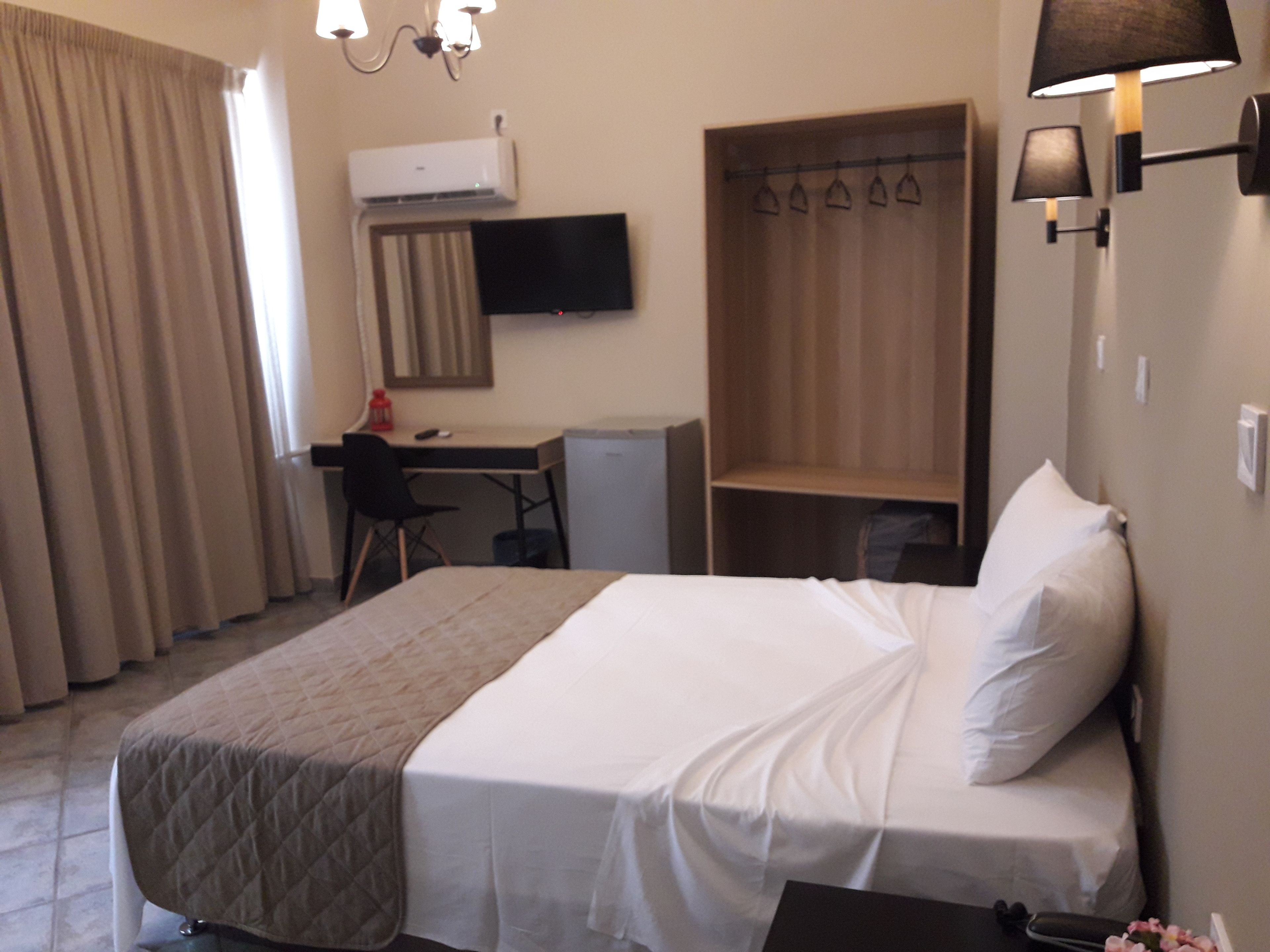 A hotel room with a bed, a desk, a chair, a wardrobe, and a TV.