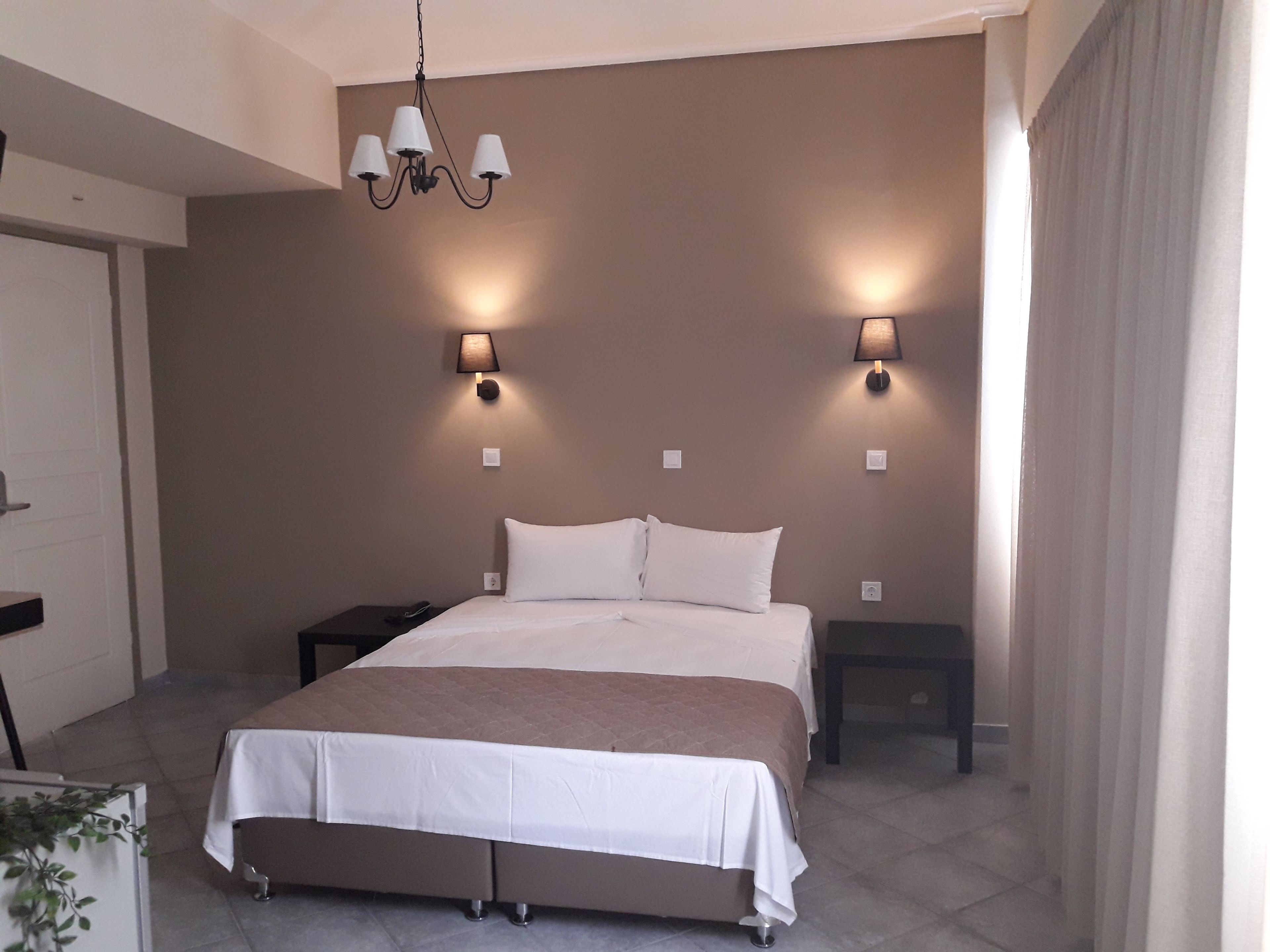 Une chambre à coucher avec un grand lit, deux tables de chevet, un luminaire suspendu et des lampes fixées au mur.