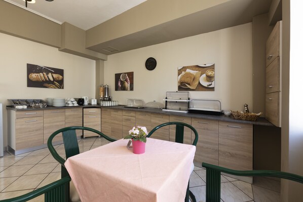 Una cocina moderna con armarios de madera, una mesa de comedor con mantel rosa y sillas verdes.
