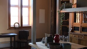 Een keuken met houten vloer, een eettafel, stoelen en een raam met een krans.