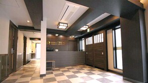 Un vestíbulo de hotel con piso a cuadros, una recepción y un letrero que dice "HOTEL TRENI ASAKUSA TOKYO KANSAI".