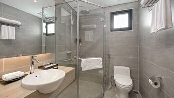 A modern bathroom with a glass-enclosed shower, a sink, a toilet, and a towel rack.