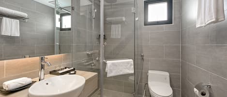 A modern bathroom with a glass-enclosed shower, a sink, a toilet, and a towel rack.