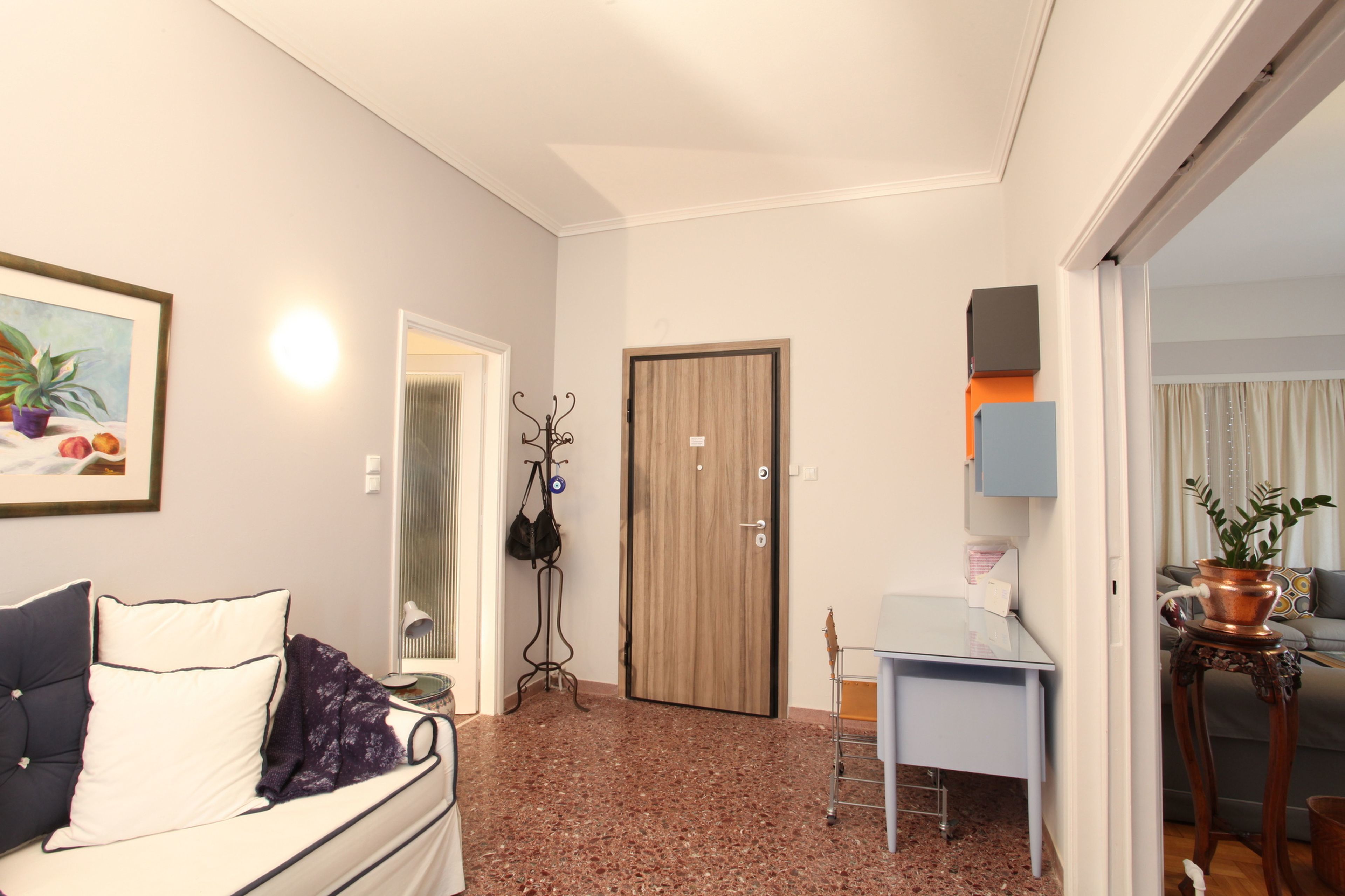 Un espacio habitable compacto con sofá, una mesita, una puerta y una planta en maceta.