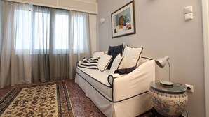 A living room with a sofa, a patterned rug, a decorative vase, and a painting on the wall. - Stylish flat by the beach of Edem (Palaio Faliro)
