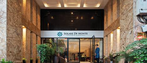 The entrance of Solare De Monte Hotel & Spa with marble steps and potted plants.
