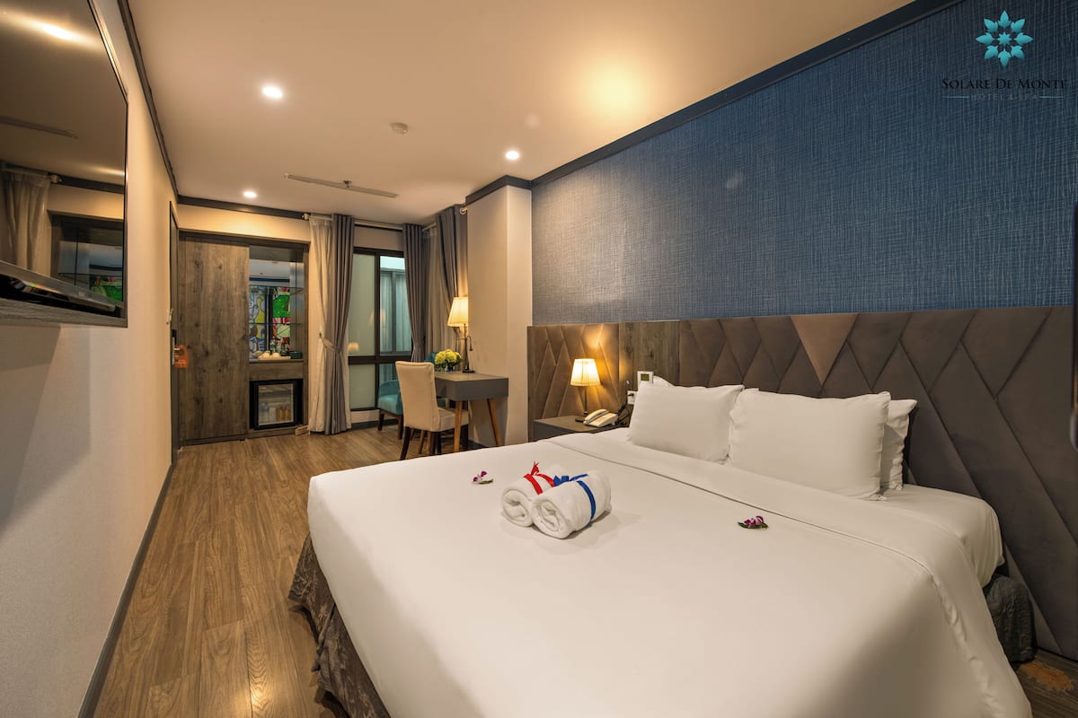 A hotel room with a large bed, a desk, and a chair.
