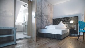 Ett modernt hotellrum med en stor säng, en stol och utsikt över badrummet.