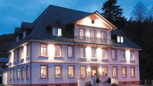 Ett hotell i två våningar med en balkong på andra våningen, flera fönster och en skylt med texten ”Landhaus Hechtberg”.