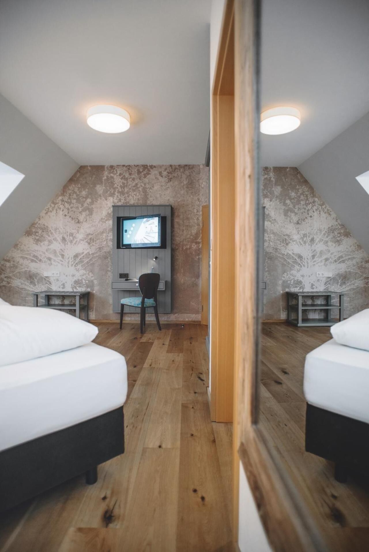 A bedroom with two beds, a desk, and a television.