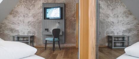 A bedroom with two beds, a desk, and a television.
