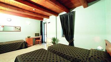 A room with two beds, a desk with a computer, a chair, and a window with curtains.